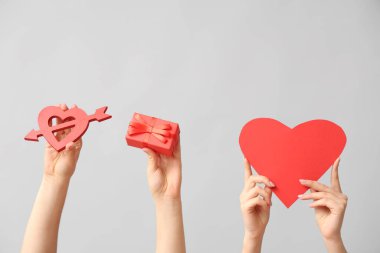 Farklı kalpleri olan kadın elleri ve gri arka planda hediye kutusu. Sevgililer Günü kutlaması