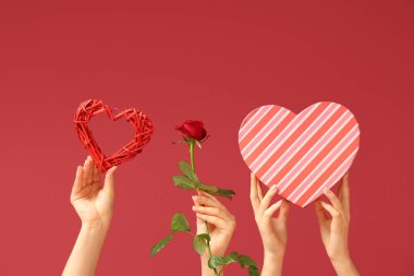 Kalbi olan bir kadın eli, kırmızı gül ve renkli bir hediye kutusu. Sevgililer Günü kutlaması