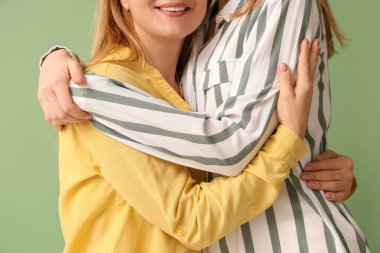 Yeşil arka planda annesine sarılan genç bir kadın. Uluslararası Sarılma Günü