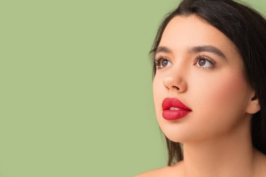 Yeşil arka planda kırmızı ruj izi olan güzel bir genç kadın. Yakın plan.