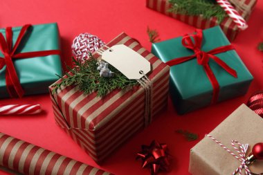 Güzel Noel hediyeleri, kırmızı arka planda ip ve ambalaj kağıdı, yakın plan.