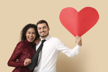 Bej arka planda Sevgililer Günü için kırmızı kalpli genç bir çift.