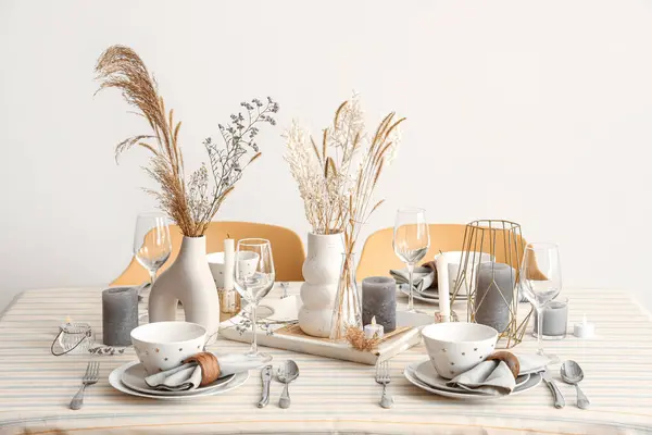 Elegant table setting with pampas grass, dried flowers and crockery in dining room