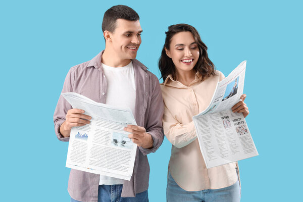 Young couple reading newspapers on blue background