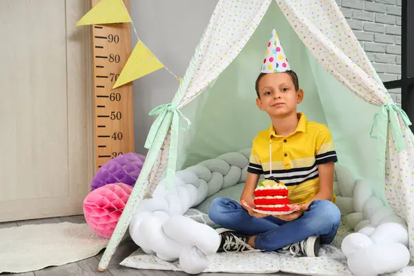 Cute little boy with Birthday cake sitting in decorated room