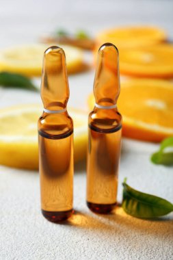 C vitamini ve beyaz fayans zemininde farklı narenciye dilimleri olan ampuller.