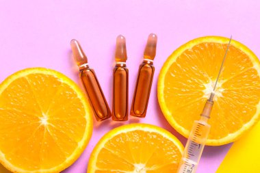 Mor zemin üzerinde C vitamini, şırınga ve portakal dilimleri olan ampuller, yakın plan.