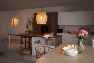 Modern mutfak, yemek masası, ada ve parlayan lambalar.