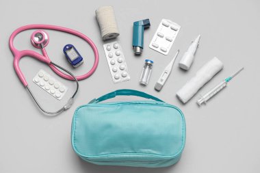 İlk yardım çantası ve gri arka planda haplar.