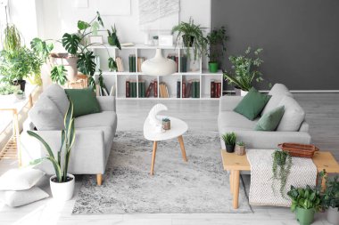 Gri kanepeleri ve çiçekleri olan modern oturma odasının içinde.