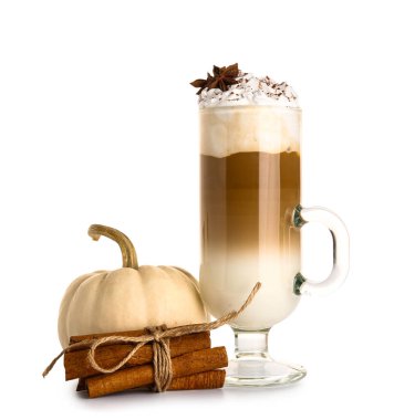 Beyaz arka planda yıldız anason ve tarçınlı bir bardak lezzetli balkabaklı latte.