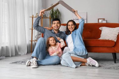 Kartonla mutlu bir aile oturma odasındaki yeni evlerini düşlüyor.