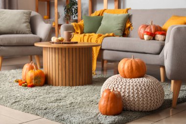 Modern oturma odasının içinde balkabağı, puf ve ahşap sehpa var.