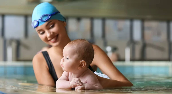 Adorable little baby with coach in swimming pool