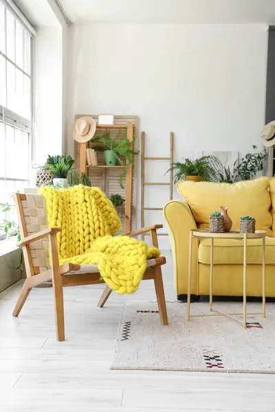 Interior of modern living room with yellow sofa, armchair and houseplants