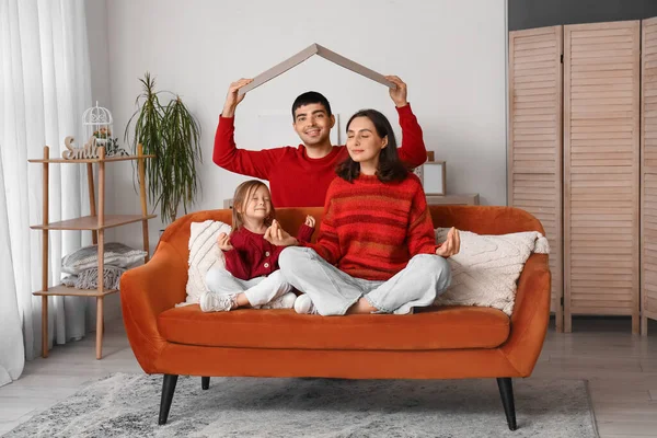 Happy family with cardboard dreaming about their new house in living room