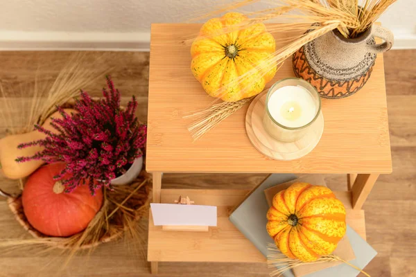 Wooden stepladder with pumpkins, books and heather flowers on floor, closeup