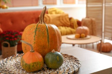 Oturma odasındaki ahşap masanın üzerinde balkabağı olan hasır paspas, yakın plan.