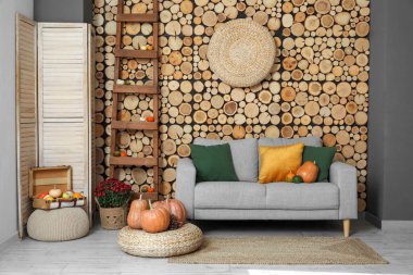 Gri kanepe, hasır puf ve balkabağı olan rahat bir oturma odası.