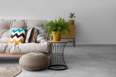 Beyaz kanepe, puf ve çiçekli aydınlık oturma odasının içinde.