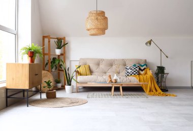 Işıl ışıl oturma odasının içinde rahat beyaz kanepe, ahşap dolap ve dekor