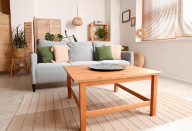 Gri kanepesi ve ahşap sehpası olan modern oturma odasının içinde.