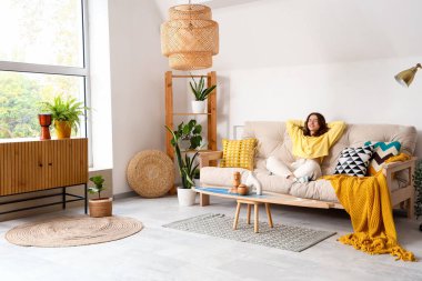 Beyaz kanepede oturan genç ve güzel bir kadın.