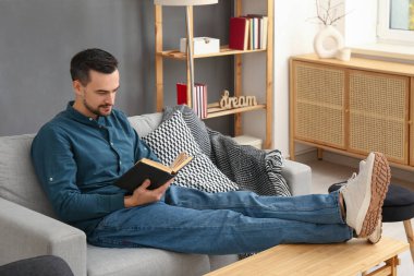 yakışıklı adam evde kanepede kitap okuma