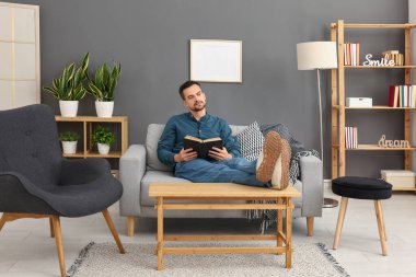 yakışıklı adam evde kanepede kitap okuma