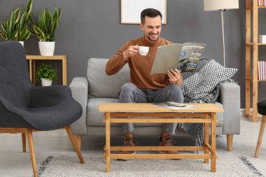 Evde kahve fincanı okuyan yakışıklı bir adam.
