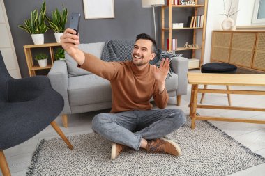 Cep telefonlu yakışıklı adam evde selfie çekiyor.