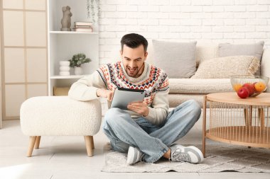 Evde tablet bilgisayar kullanan yakışıklı bir adam.