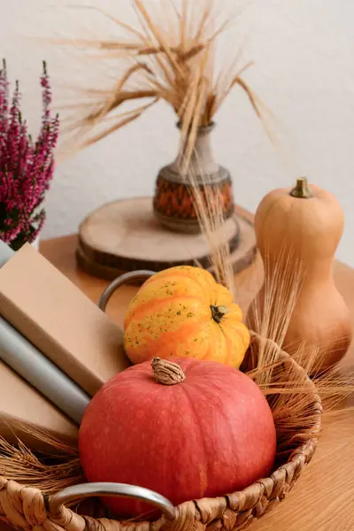 Autumn still life with pumpkins, books and wheat ears on wooden table, closeup