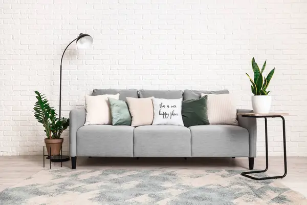 Interior of modern living room with grey sofa, standard lamp and houseplants
