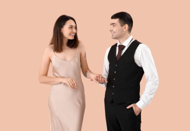 Bej arka planda el ele tutuşan zarif genç bir çift.