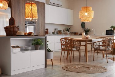 Modern mutfak, yemek masası, ada ve parlayan lambalar.