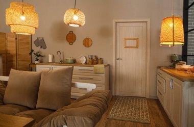 Akşamları parıldayan lambalar, kanepe ve beyaz tezgahlı modern mutfak.