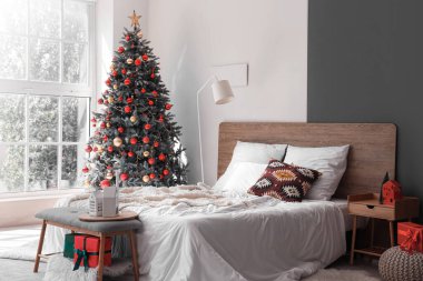 Konforlu yatağı ve Noel ağacı olan şenlikli bir yatak odası.