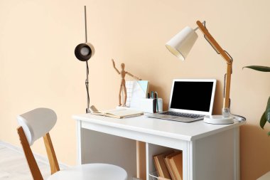 Modern dizüstü bilgisayarı ve renk duvarına yakın kırtasiyesi olan rahat bir iş yeri