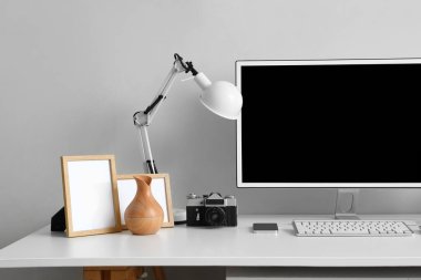 Modern bilgisayar ve ışık duvarının yanında fotoğraf makinesi olan şık bir iş yeri.