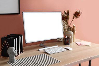 Modern bilgisayar, kırtasiye ve dekorasyon renkli duvarın yanındaki ahşap masada.