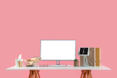 Pembe arka planda modern bilgisayarı ve kırtasiyesi olan rahat bir iş yeri
