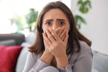 Evdeki oturma odasında güzel, genç, korkmuş bir kadın.