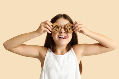 Mutlu küçük kız bej arka planda tatlı çikolatalı kurabiyeler tutuyor.