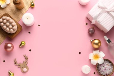 Spa aksesuarları, Noel süslemeleri ve pembe arka planda hediye kutusu olan kompozisyon