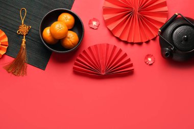 Mandalinalı çaydanlık ve kırmızı arka planda oryantal semboller. Yeni yıl kutlaması