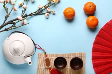 Mavi arka planda fincanlı çaydanlık, mandalina ve sakura. Yeni yıl kutlaması