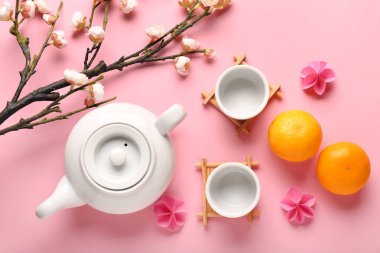 Fincanlı çaydanlık, mandalina ve pembe arka planda sakura. Japon Yeni Yıl Kutlaması