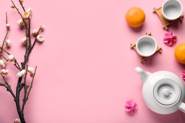 Fincanlı çaydanlık, mandalina ve pembe arka planda sakura. Japon Yeni Yıl Kutlaması