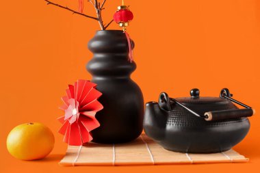 Dal dallı vazo, oryantal semboller ve turuncu arka planda çaydanlık. Yeni yıl kutlaması